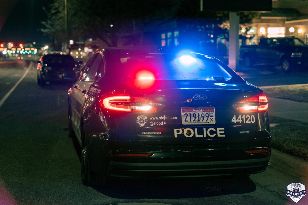A picture of the back of a police car with the red and blue lights on