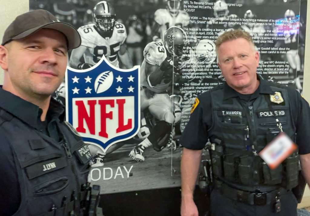 Photo of two police officers in front of an NFL sign.